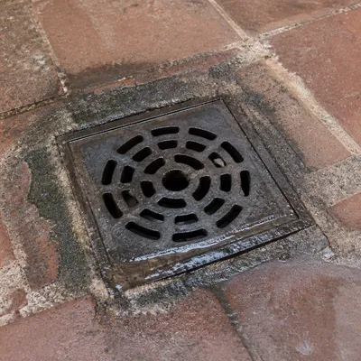 Rejilla de desagüe en un patio de Zaragoza donde se percibe olor a alcantarilla